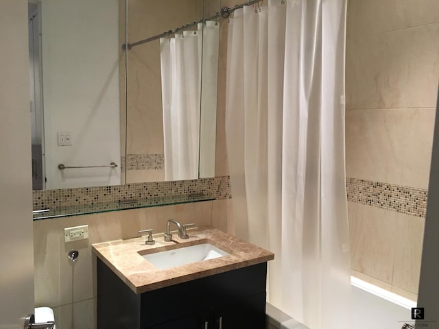 full bathroom with tile walls, backsplash, and vanity