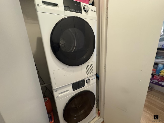 washroom featuring laundry area, wood finished floors, and stacked washer and clothes dryer