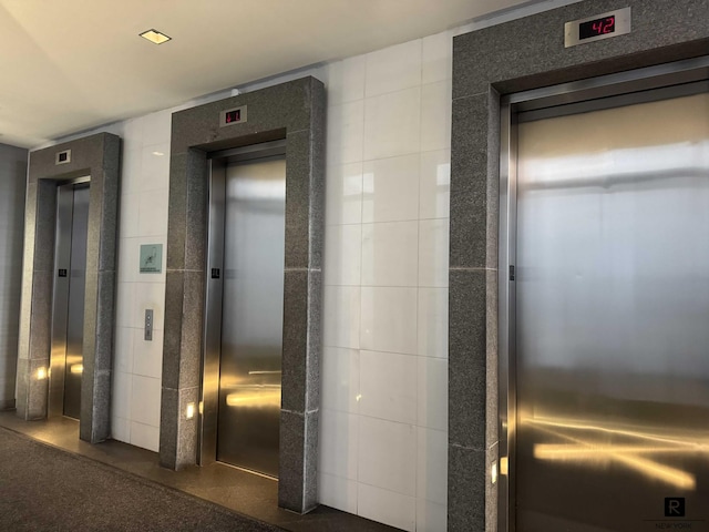 hall featuring tile walls and elevator