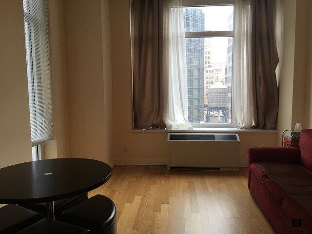 sitting room featuring light wood-type flooring, baseboards, and radiator heating unit