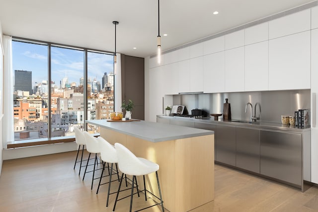 251 W 14th Street Penthouse, New York City, NY 10011 - kitchen with modern cabinets, light wood-style flooring, a skyline view, a center island, and a kitchen bar