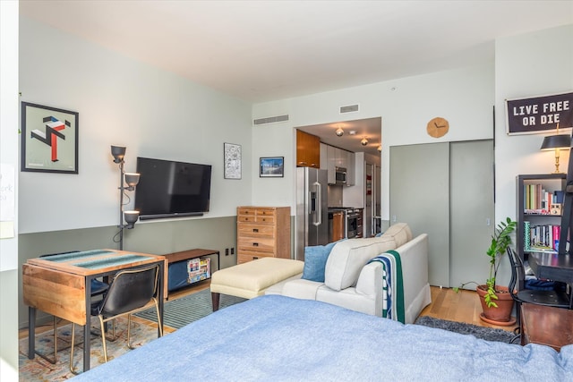 bedroom with visible vents, high quality fridge, and wood finished floors