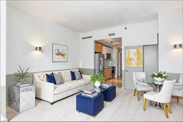 living area featuring wood finished floors, a wealth of natural light, and a baseboard radiator