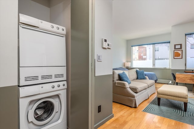 laundry room with stacked washer and clothes dryer, wood finished floors, and laundry area