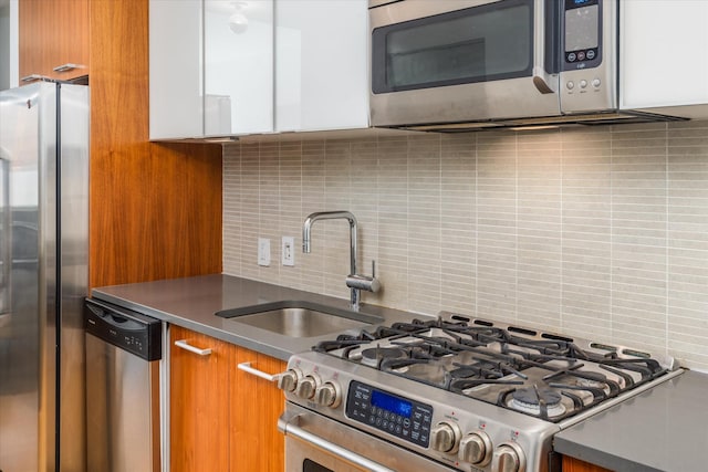 kitchen with a sink, dark countertops, tasteful backsplash, appliances with stainless steel finishes, and brown cabinetry