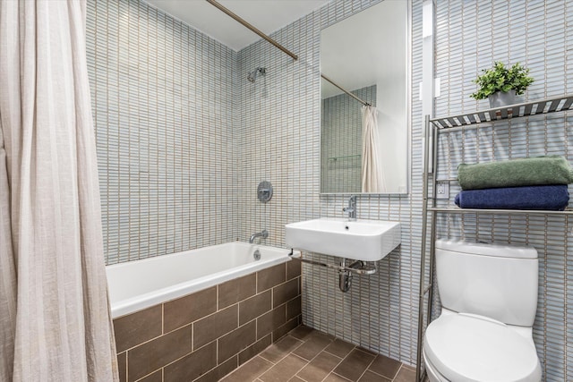 full bath with tiled shower / bath, toilet, a sink, tile walls, and tile patterned flooring