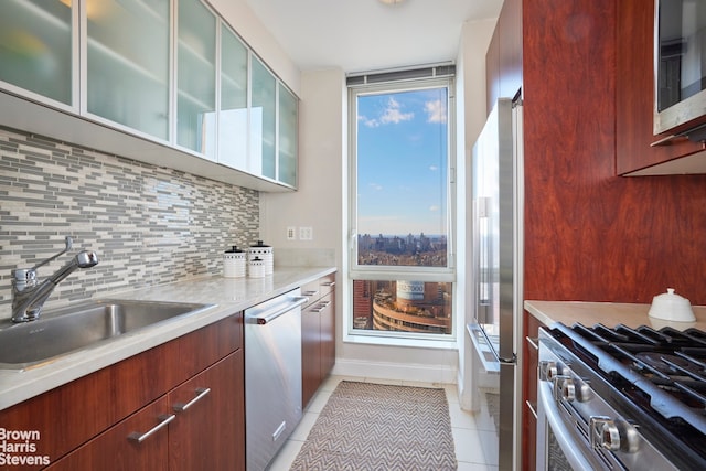 kitchen featuring tasteful backsplash, appliances with stainless steel finishes, light tile patterned flooring, a sink, and modern cabinets