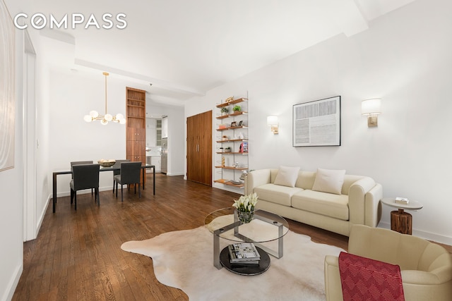 living room with dark wood-type flooring, a notable chandelier, and baseboards