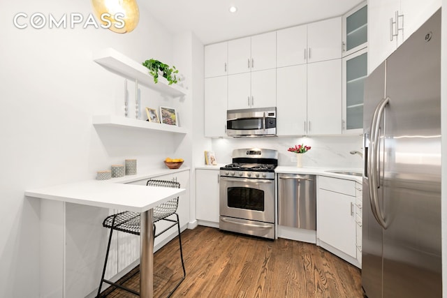 kitchen with a sink, dark wood-style floors, stainless steel appliances, white cabinets, and light countertops