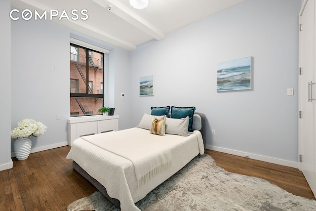 bedroom featuring beamed ceiling, baseboards, and wood finished floors