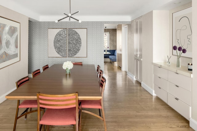 dining space featuring wallpapered walls, baseboards, and light wood-style floors