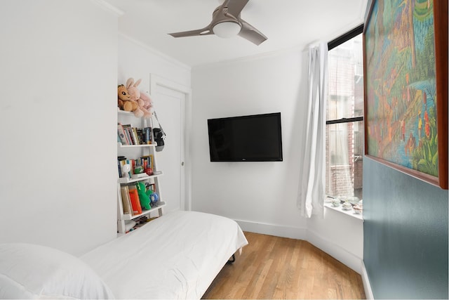 bedroom featuring a ceiling fan, baseboards, crown molding, and wood finished floors