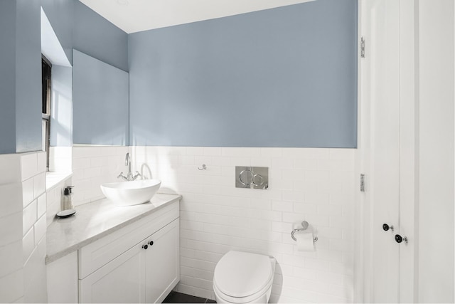 bathroom featuring wainscoting, vanity, toilet, and tile walls