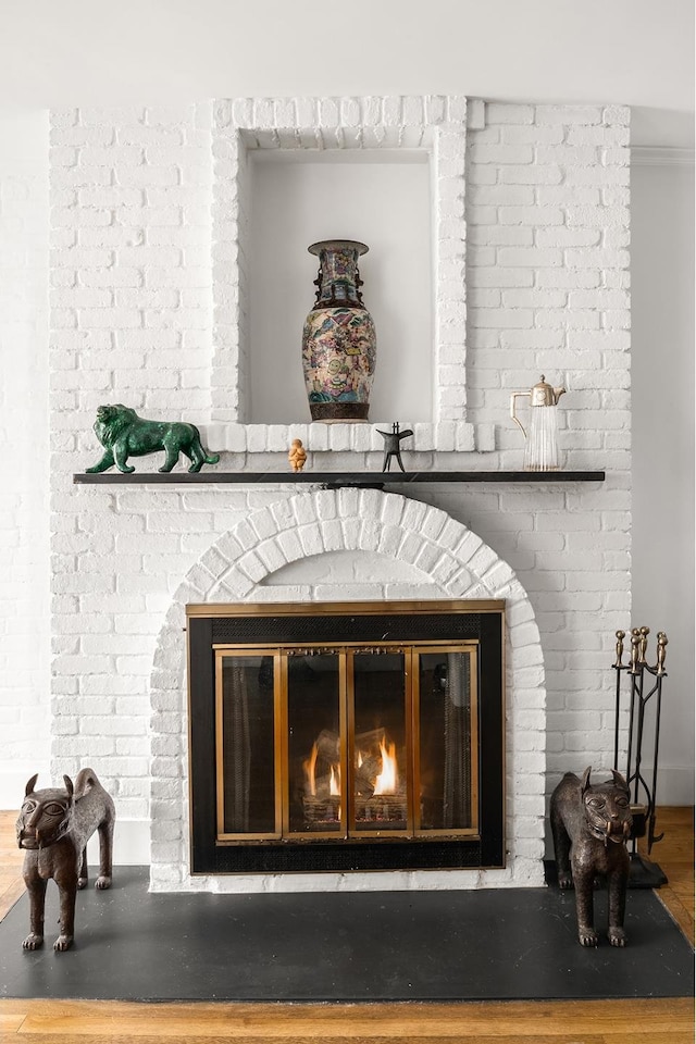 details featuring a brick fireplace and wood finished floors