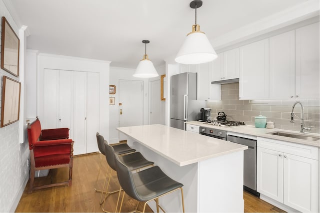 kitchen with white cabinets, stainless steel appliances, a sink, and wood finished floors