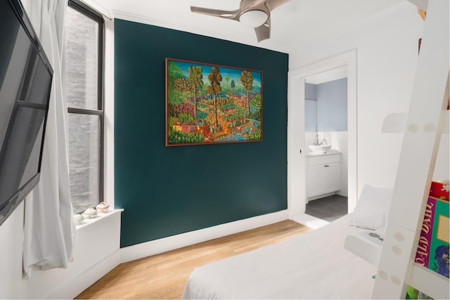 bedroom with ornamental molding, ensuite bath, baseboards, and wood finished floors