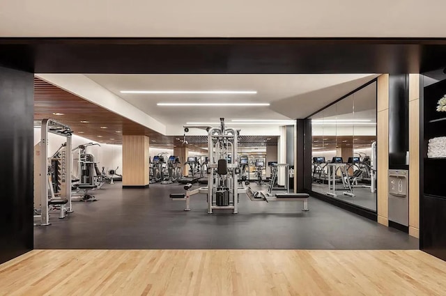 gym featuring wood finished floors and a chandelier