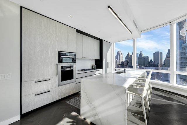 kitchen featuring a breakfast bar area, a sink, light stone countertops, a view of city, and modern cabinets