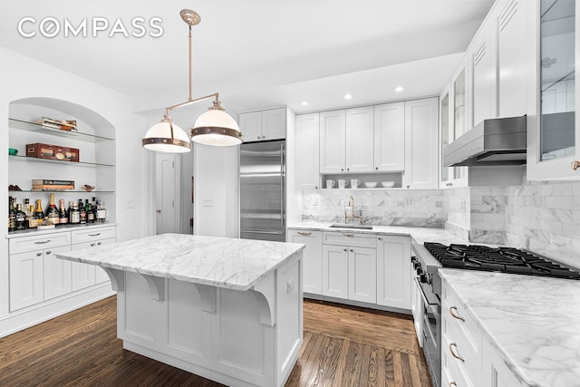 kitchen with wall chimney exhaust hood, dark wood-style floors, premium appliances, and a center island