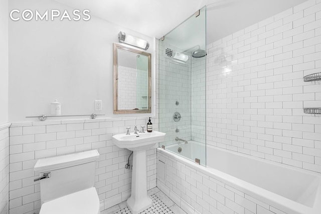 410 W 24th St Unit 6J, New York City, NY 10011 - bathroom with tile walls, toilet, tiled shower / bath, tile patterned flooring, and a wainscoted wall