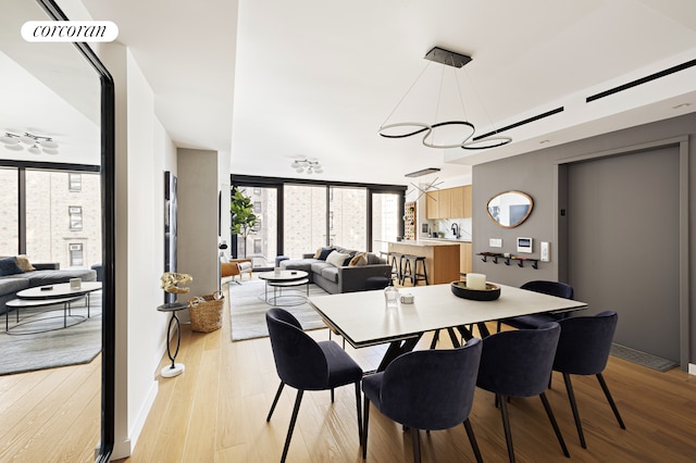 dining area with light wood-style flooring, floor to ceiling windows, and a chandelier