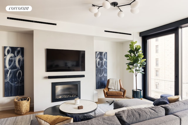 living room with baseboards, visible vents, a glass covered fireplace, wood finished floors, and floor to ceiling windows