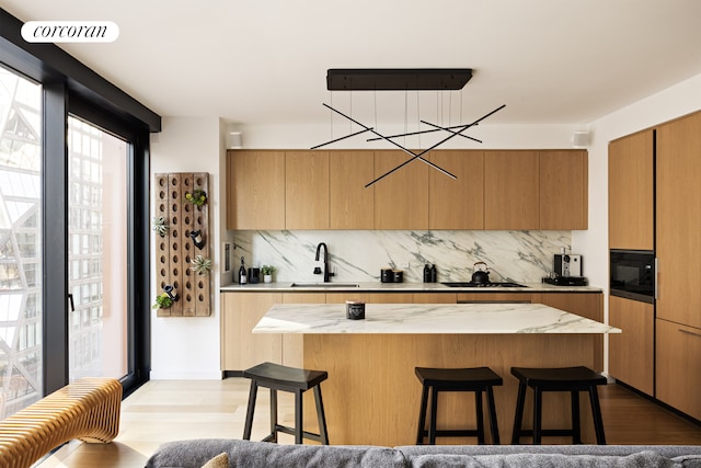 kitchen with a kitchen bar, black microwave, decorative backsplash, and a sink