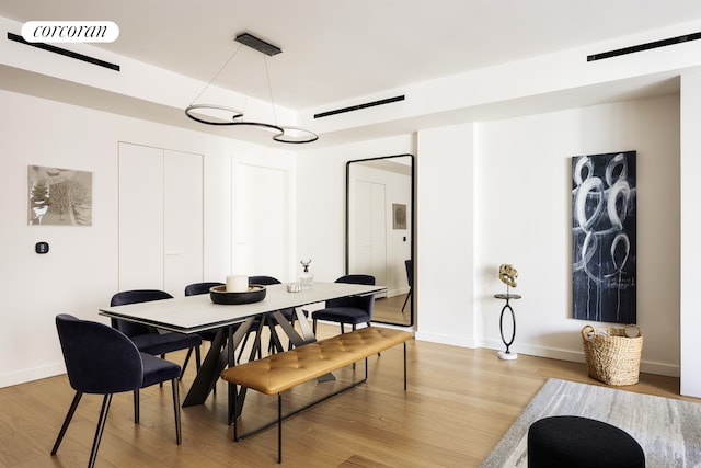 dining room featuring light wood finished floors, baseboards, and visible vents