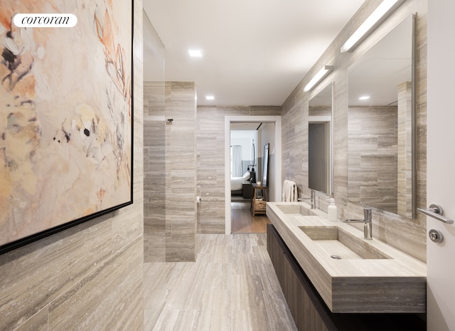 bathroom with double vanity, a sink, and tile walls