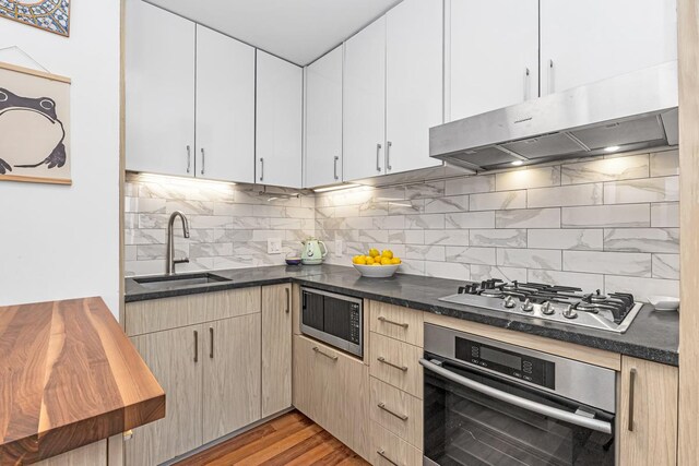206 E 95th St Unit 7C, New York City, NY 10128 - kitchen with under cabinet range hood, tasteful backsplash, stainless steel appliances, and a sink