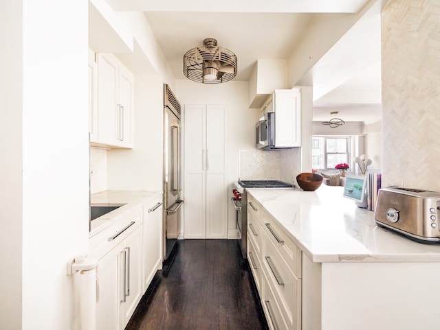 kitchen featuring white cabinetry, dark wood-type flooring, backsplash, light stone counters, and high end appliances