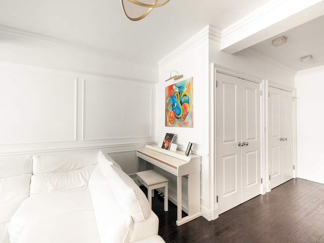 bedroom with a decorative wall, ornamental molding, multiple closets, and dark wood finished floors