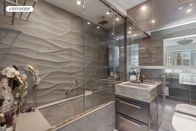 bathroom featuring a shower with door, tile walls, and vanity