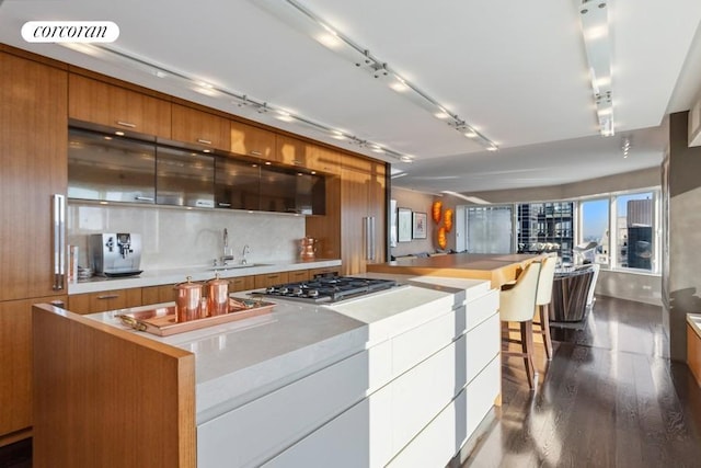 kitchen featuring dark wood-style floors, brown cabinetry, modern cabinets, and a sink