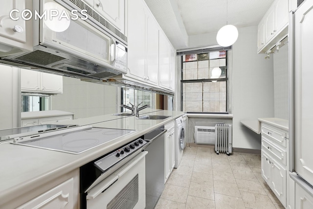 kitchen featuring wall oven, white microwave, cooktop, and white cabinetry