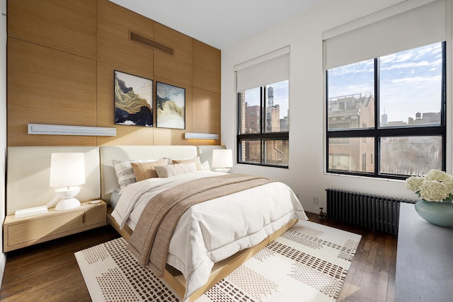 bedroom featuring radiator, a view of city, visible vents, and dark wood-type flooring