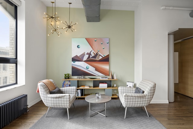 living area featuring radiator, baseboards, a notable chandelier, and wood finished floors