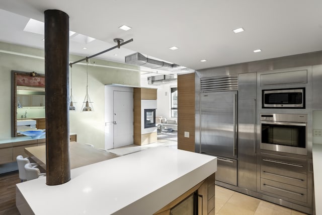 kitchen featuring recessed lighting, open floor plan, light countertops, and built in appliances