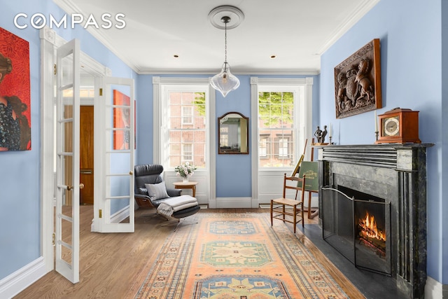 sitting room with french doors, wood finished floors, ornamental molding, and a high end fireplace