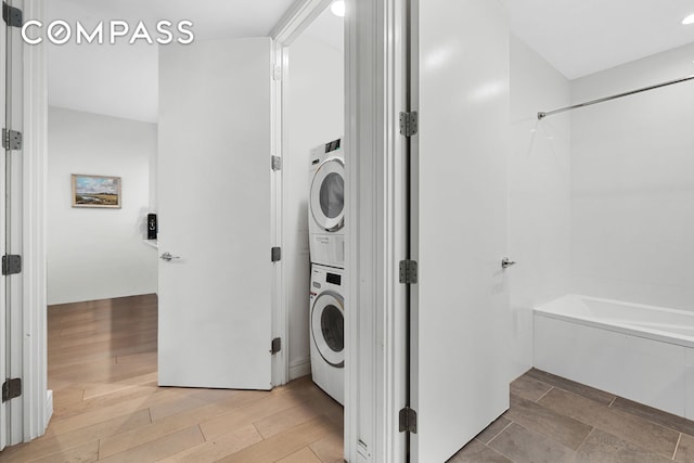 clothes washing area with light wood-type flooring, stacked washer / dryer, and laundry area