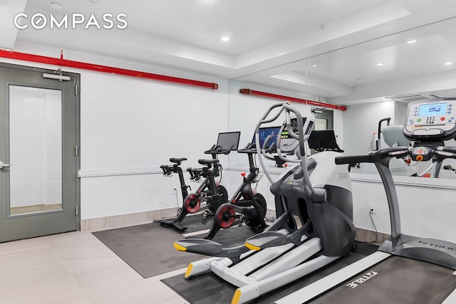 workout room featuring a tray ceiling and recessed lighting