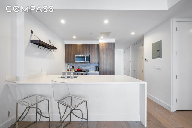 kitchen featuring light countertops, stainless steel microwave, a sink, modern cabinets, and a peninsula