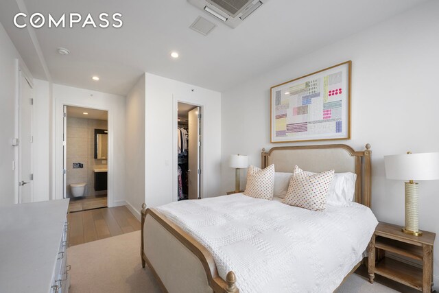 bedroom featuring connected bathroom, recessed lighting, light wood-style floors, a closet, and a walk in closet