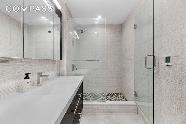 bathroom with decorative backsplash, tile walls, a shower stall, and vanity