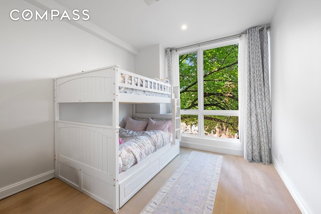 bedroom featuring multiple windows, baseboards, and wood finished floors