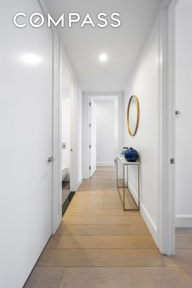 hall with light wood-type flooring and baseboards