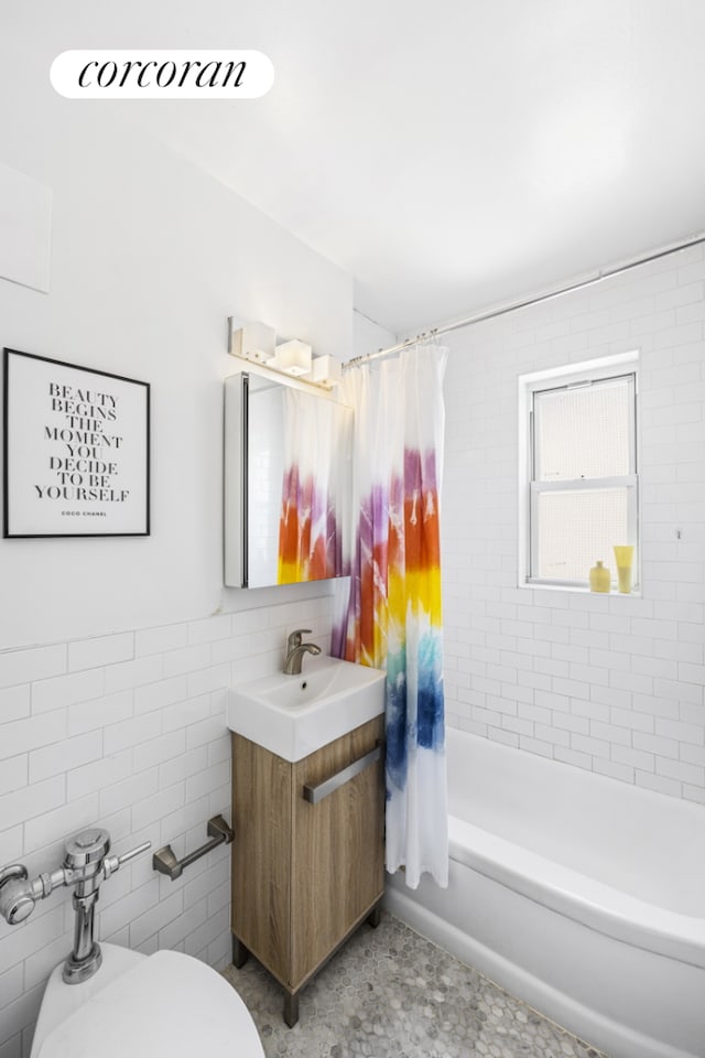 full bath featuring toilet, shower / bath combo, vanity, and tile walls