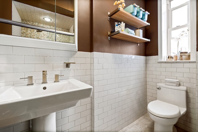 bathroom featuring a wainscoted wall, toilet, and tile walls