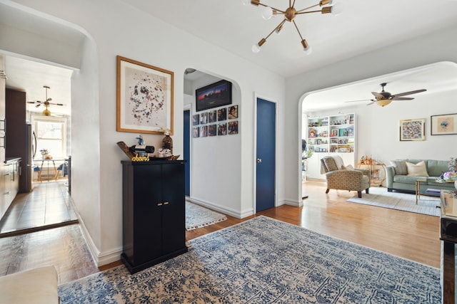 corridor with an inviting chandelier, baseboards, arched walkways, and wood finished floors