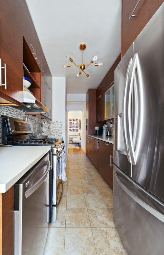 kitchen featuring tasteful backsplash, stainless steel appliances, light countertops, and an inviting chandelier